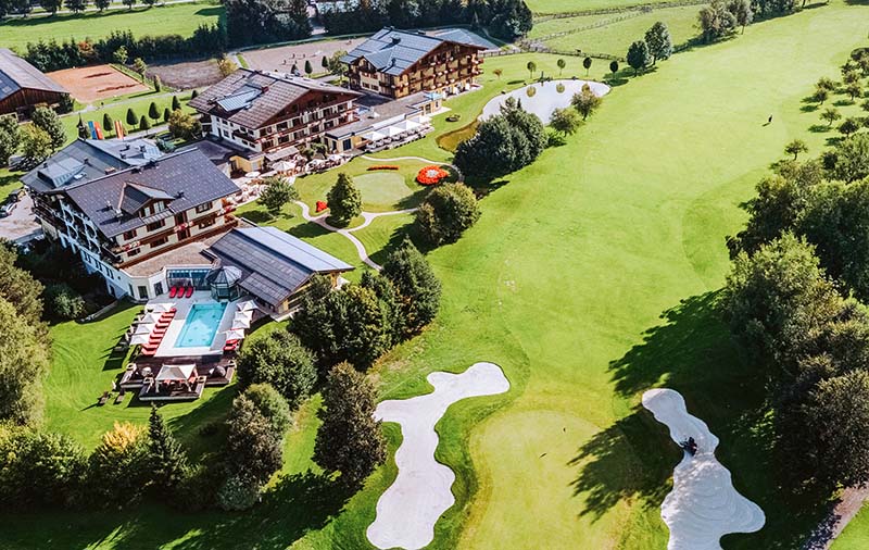 Luftaufnahme vom Partnerhotel Gut Weissenhof und einer Spielbahn des Golfplatzes